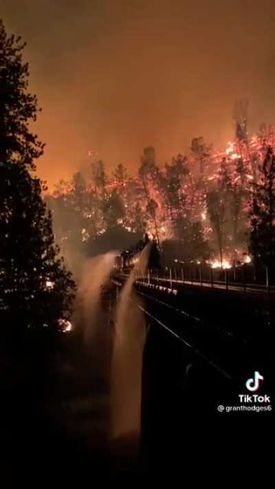Amazing visual of a train watering down a bridge to try to save it from the fire