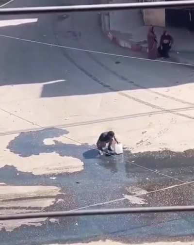 &ldquo;A desperate Palestinian collects spilled water after Israel&rsquo;s attack destroyed the neighborhood's water tank.&ldquo;