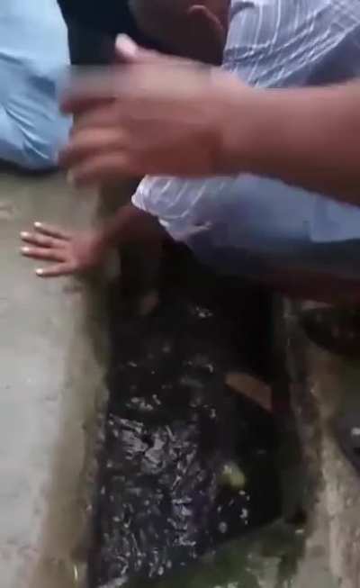 An elderly man trips and falls into an open drain.