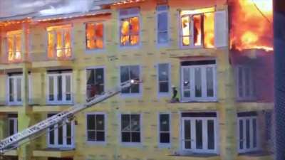 Construction worker cornered by a fire at the top of building