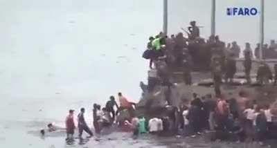 merciless spanish officers push people into sea as thousands of migrants cross border.