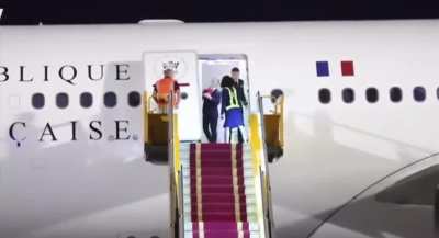 Emmanuel Macron pushed by wife while getting off a plane.