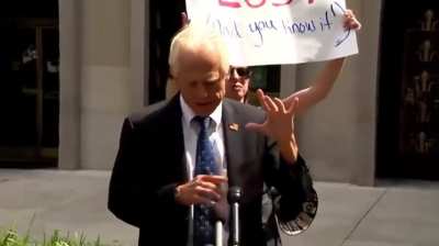Peter Navarro tries to rip down a Trump Lost sign, and fails