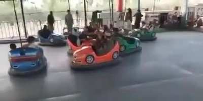 Taliban playing on the bumper cars with some kids.