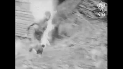 Burning Japanese soldier walks out of his position after a Australian flamethrower hits it (Balikpapan Indonesia 1945)