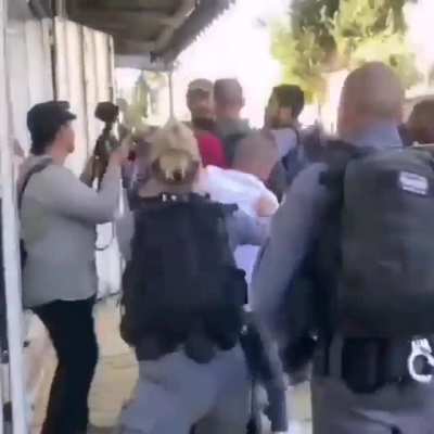A man shields an elderly Palestinian woman from Israeli Occupation Forces who push them out to make way for Israelis participating in today's "March of the Flags" through occupied East Jerusalem.
