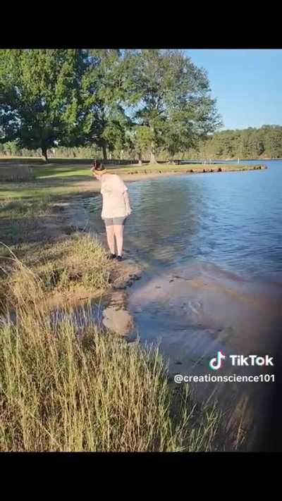 Bravely jumping over calm stream of water