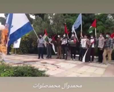 Palestinians burning isreali flag .