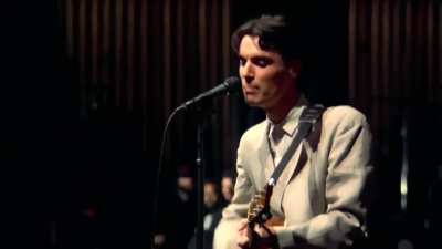 David Byrne performing "Psycho Killer" with a portable cassette tape player and an acoustic guitar during the beginning of Stop Making Sense, December 1983.