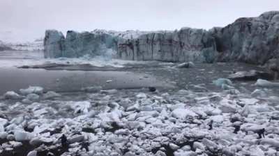 Tourists watch and scramble for cover as a huge chunk of the Brei&eth;amerkurj&ouml;kull glacier calves. The scale is hard to imagine until you see the waves.