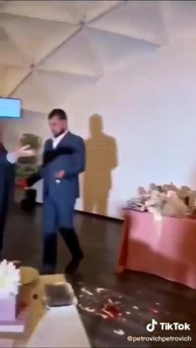 Guest destroys wedding cake and tries to throw it at the bride and groom, then gets a punch to the face.