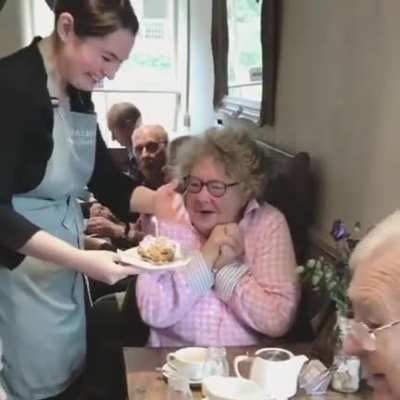 Sweet lady reacting to a free birthday cake at a diner she regularly visits.