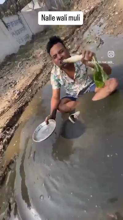 Indian man eating radish dipping in sewage