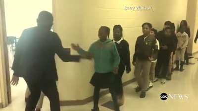 Teacher greets students with a unique handshake into class