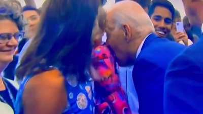 Biden nibbles on baby then attempts to sniff her.