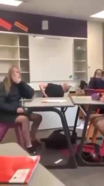 Man tries to stand upside down on his hands on a table in a reading room