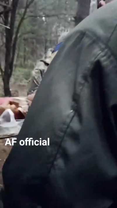Ukrainian soldiers happily queue for their meal at a field kitchen in the woods.