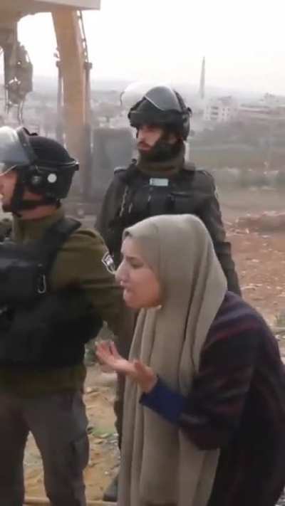 Women trying to stop the demolition of their home as armed soldiers try to enforce it