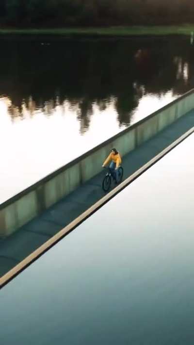 There is a bike trail in Belgium where you can go &ldquo;Cycling Through Water,&rdquo; through a large lake in the De Wijers nature reserve. This bridge is below the water line and in parts it is low enough to put riders at eye level with the lake.