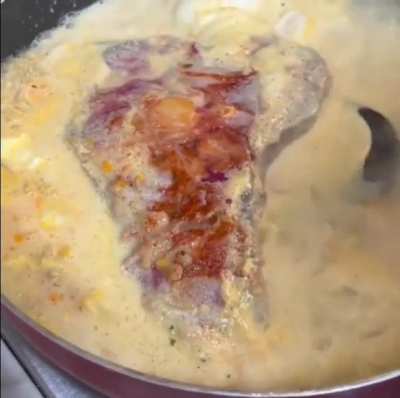 Steak in a frying pan with macaroni , cheese and egg