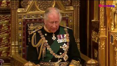 English monarch announces the government's top priority is to "help ease the cost-of-living for families" while sitting on a gold throne next to a crown encrusted with 3,000 diamonds