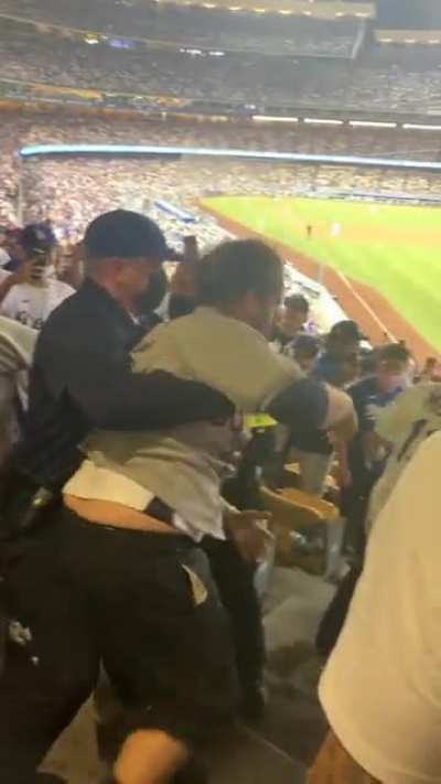 A solid view of a Dodgers fan head butting an Astros as he being escorted by security