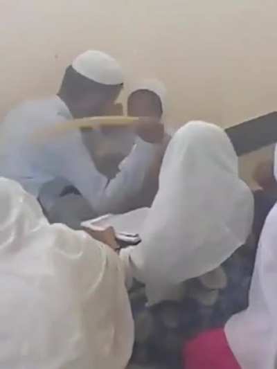 Teacher hitting his student for not memorizing the Quran.