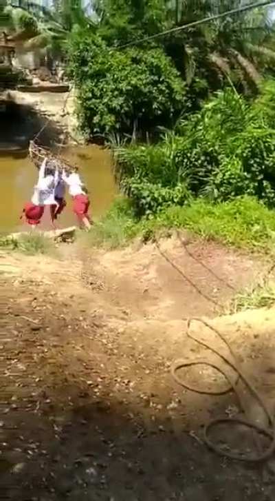Schoolchildren in a remote Indonesian village have to go "Indiana Jones style" to cross a river to get to their School. Source:  