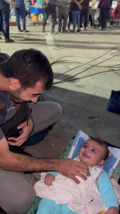 Palestinian journalist plays with a baby that survived the Israeli bombings