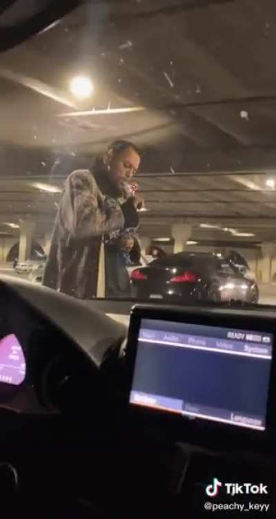 Meth head hits the pipe in front of a large crowd at a parking garage