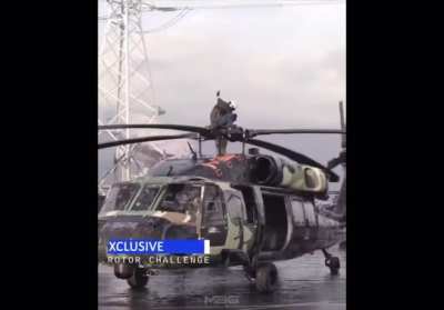 Guy stands on the top of spinning helicopter rotor