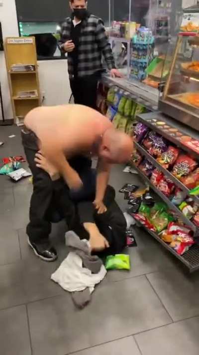 Two guys fighting at a gas station
