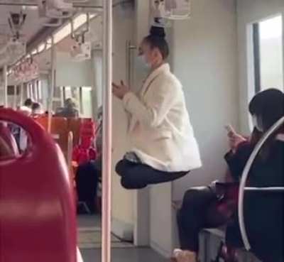 Woman swings off a subway handrail by her hair