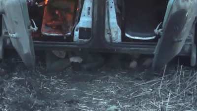 Russian soldiers are hiding under a destroyed and burning infantry fighting vehicle.