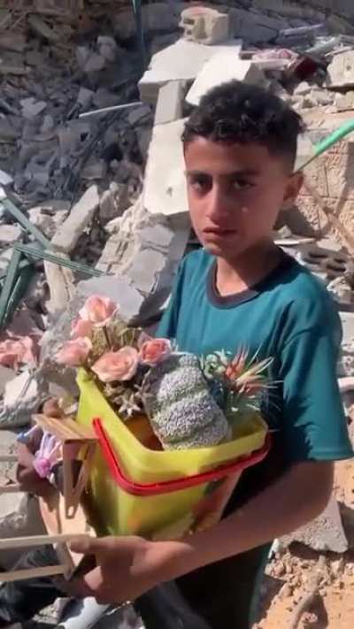 A child in Gaza Puts what's left of his childhood into a bucket after Israeli Airstrikes Leveled his home