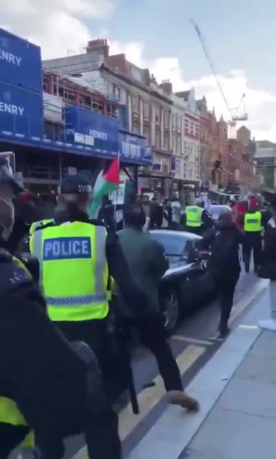 People trying to vandalize a car during a protest in London.