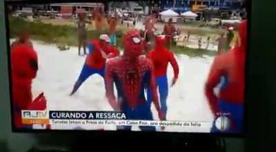 A reporter was talking about the amount of poeple coming to the beach when a group of spider-mans came into frame dancing, jumping and rolling