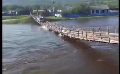 Over confident driver uses a rickety bridge that's being overtaken by a swollen river