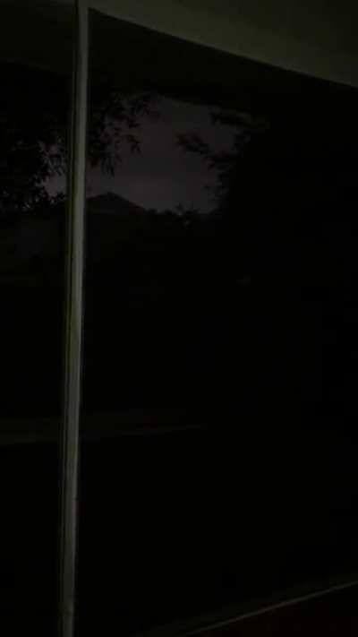 Dark rainstorm on an old Florida lanai with low lying thunder, and anoles/frogs you can&rsquo;t see on the screen