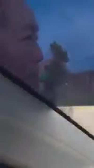 Women holds onto mans car as he drives off