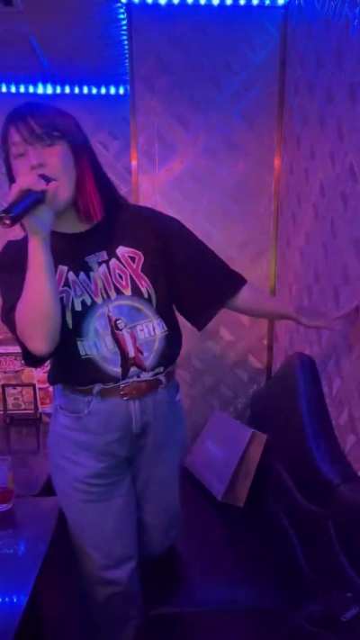 Hikaru Shida singing "Demon World War" at a karaoke
