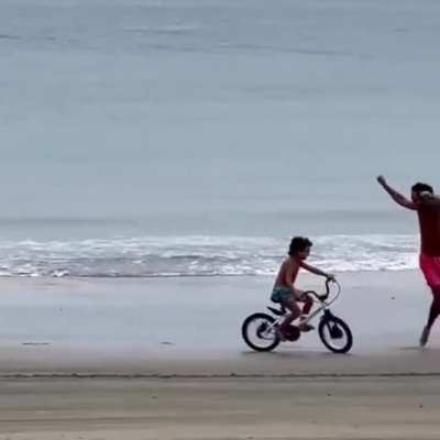 Father is ecstatic as his son learns to ride a bike