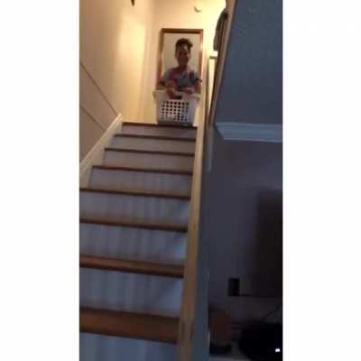 Trying to slide down the stairs in a laundry basket