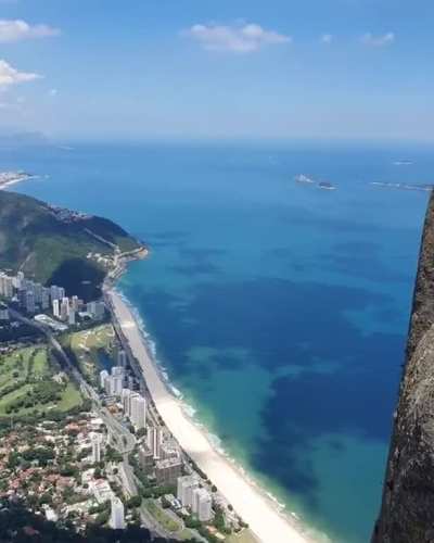 A tourist sitting on top of the Pedra da G&aacute;vea Mountain, Brazil