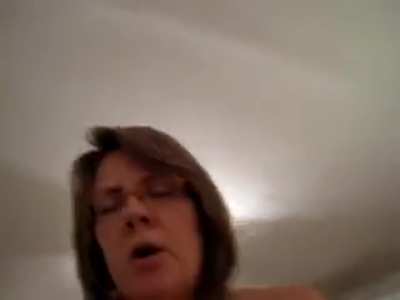 POV of a MILF in glasses riding cowgirl on a cock. She encourages her partner to cum for her before she starts cumming herself, announcing her orgasm with 