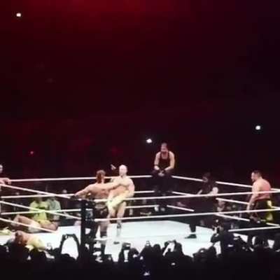 Seth Rollins jumping over Kofi while Cesaro performs the Cesaro Swing on him