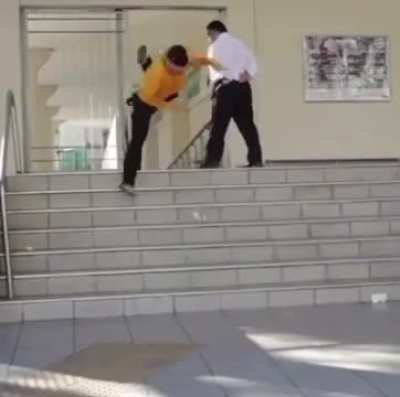 Security guard stops skaters board during trick.