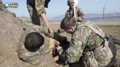 2 wounded Azerbaijani soldiers treated by Armenian soldiers on site and then transported to a hospital while a white flag is being waved.