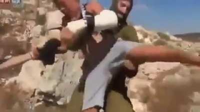 An armed Israeli soldier tries to arrest a Palestinian child by sitting on him and suffocating him without any consideration to the child's crying and pain from his broken hand. The child's family succeeded in ridding him from the soldier later. By: @&zwnj;&zwnj;&lrm;R