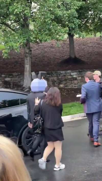 One of Trump’s crypto investors entering his event wearing a mask while protestors shout, 